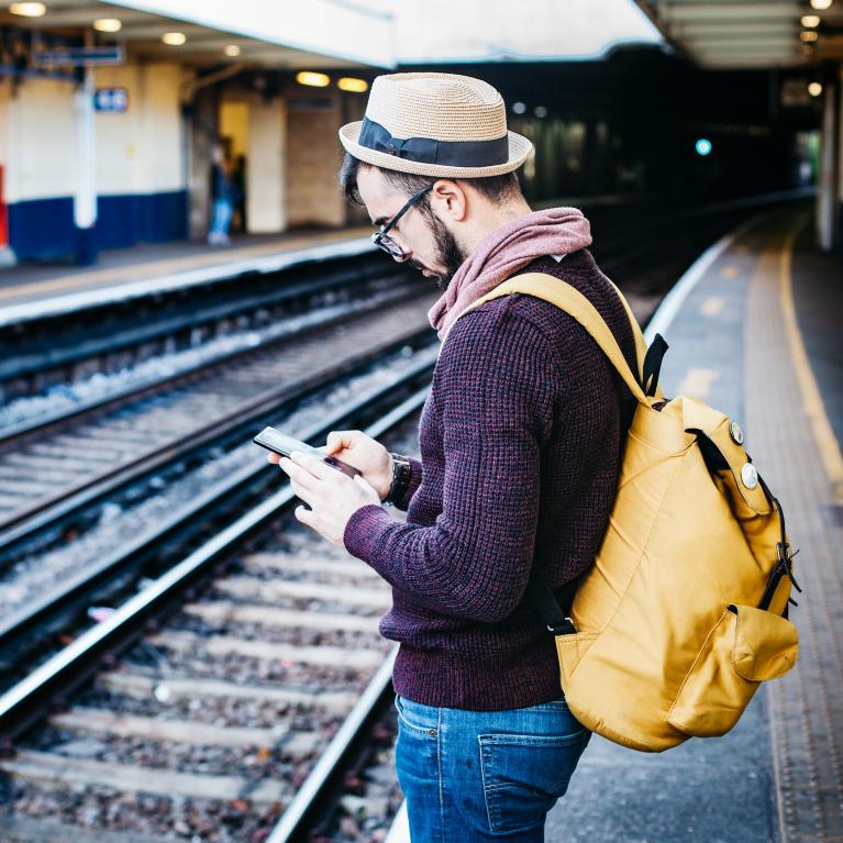 Man reading on phone at train station
