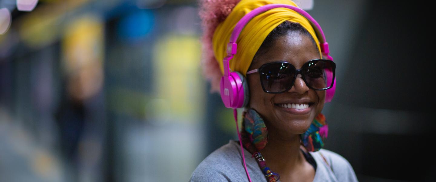 a woman smiling she is wearing headphones and black sunglasses